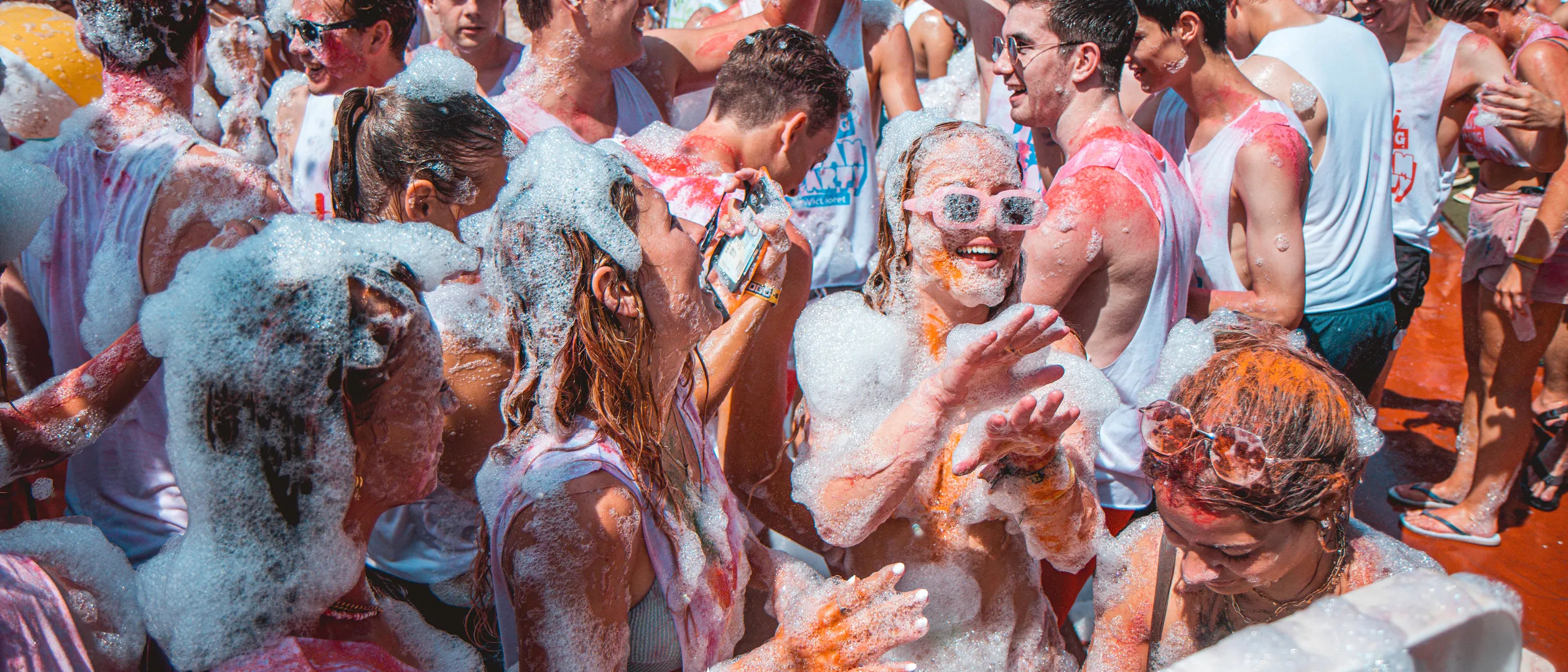Meisjes die lachen op een Summer Bash color foamparty op jongerenreis, terwijl ze plezier maken met vrienden.